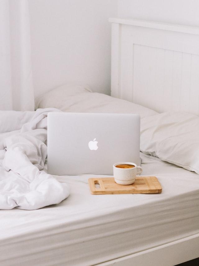 Laptop and coffee sitting on a bed